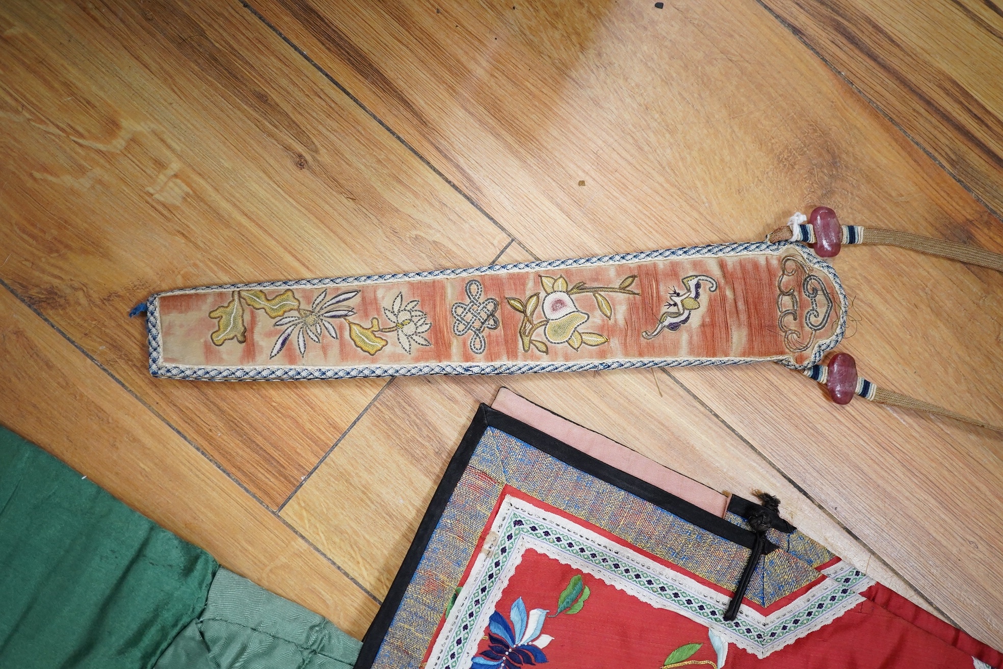 A Chinese embroidered fan case, a small red silk embroidered robe, trousers and a later pair of embroidered slippers, the robe possibly for a child, 20th century, embroidered with multi-coloured flowers and gold thread o